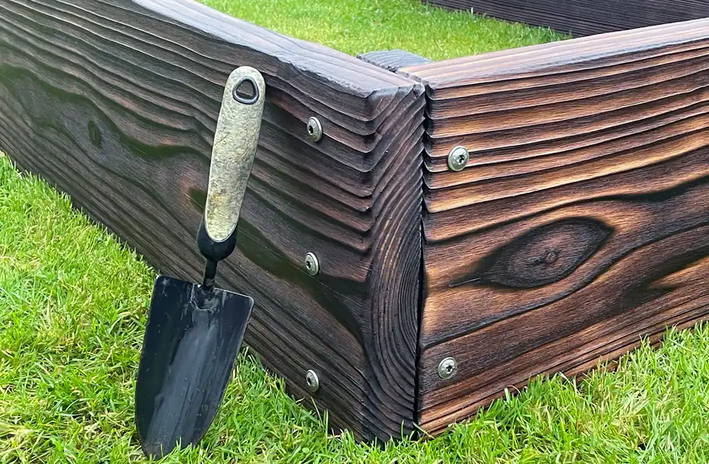 Structural screws with wide heads used in a raised bed corner to spread load and resist outward soil pressure