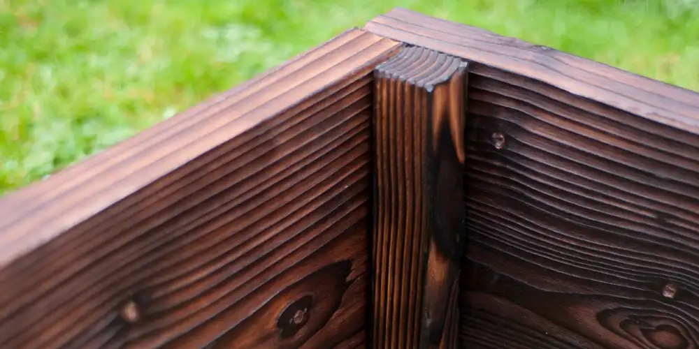 A raised bed corner is where pressure from two loaded walls meets, so the joint needs support, fixing strength and enough timber around the screws