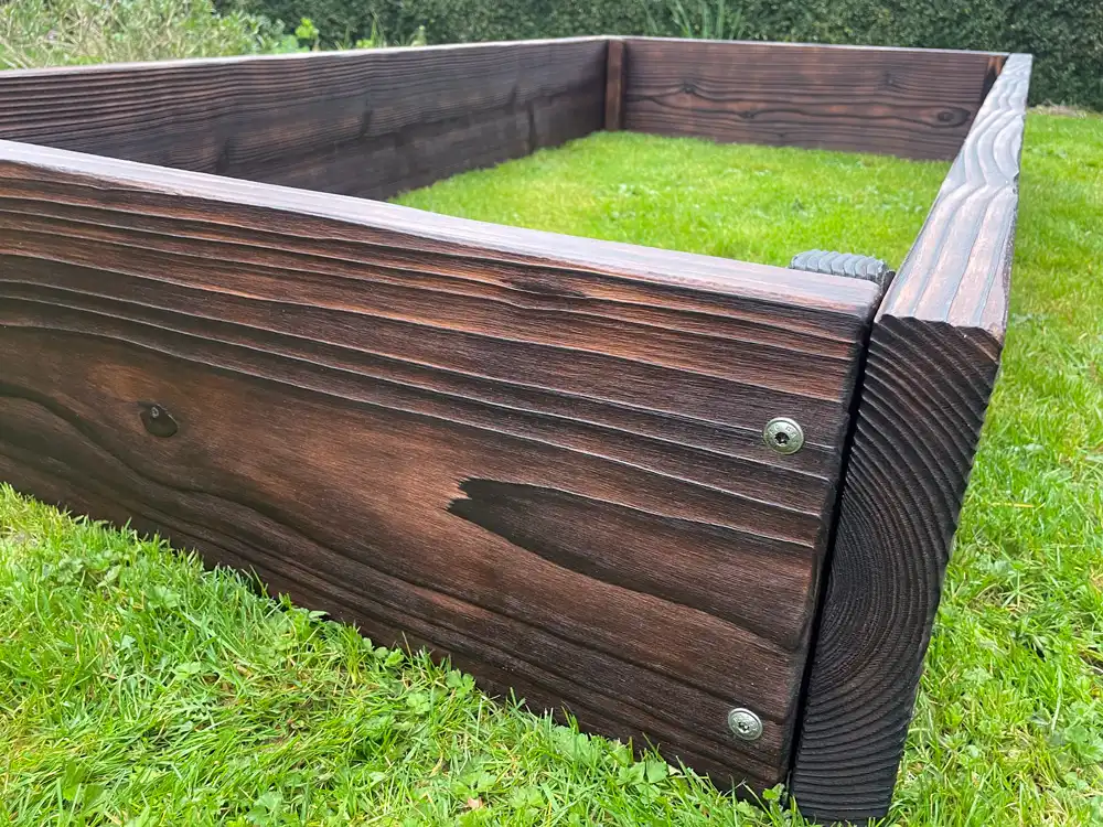 Open-bottom raised bed on grass showing root-zone connection with the ground below