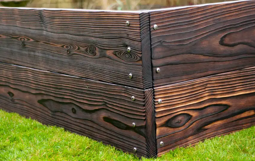 Corner detail of a Yakisugi Western Red Cedar raised bed showing thick timber boards and structural fixings