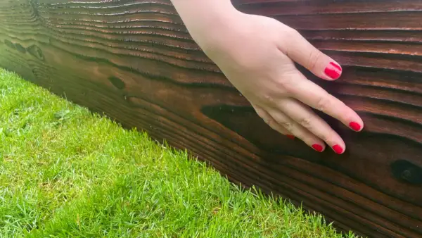 Hand touching the brushed Yakisugi surface of a Western Red Cedar raised bed